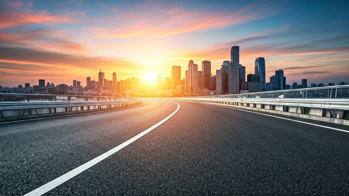 A winding road leading to a futuristic city at dawn, symbolizing focusing on future opportunities and leaving past problems behind.