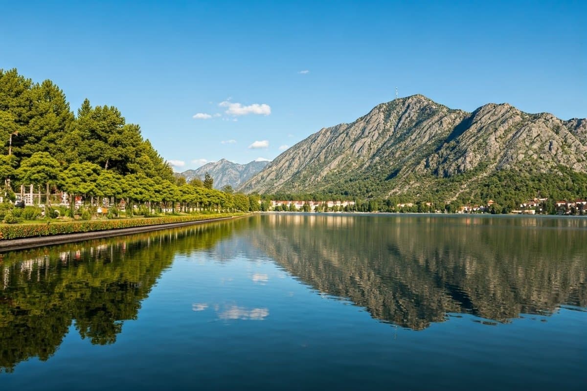 A landscape depicting a calm lake with a flourishing garden on one side and a rugged mountain range on the other, symbolizing control and acceptance.